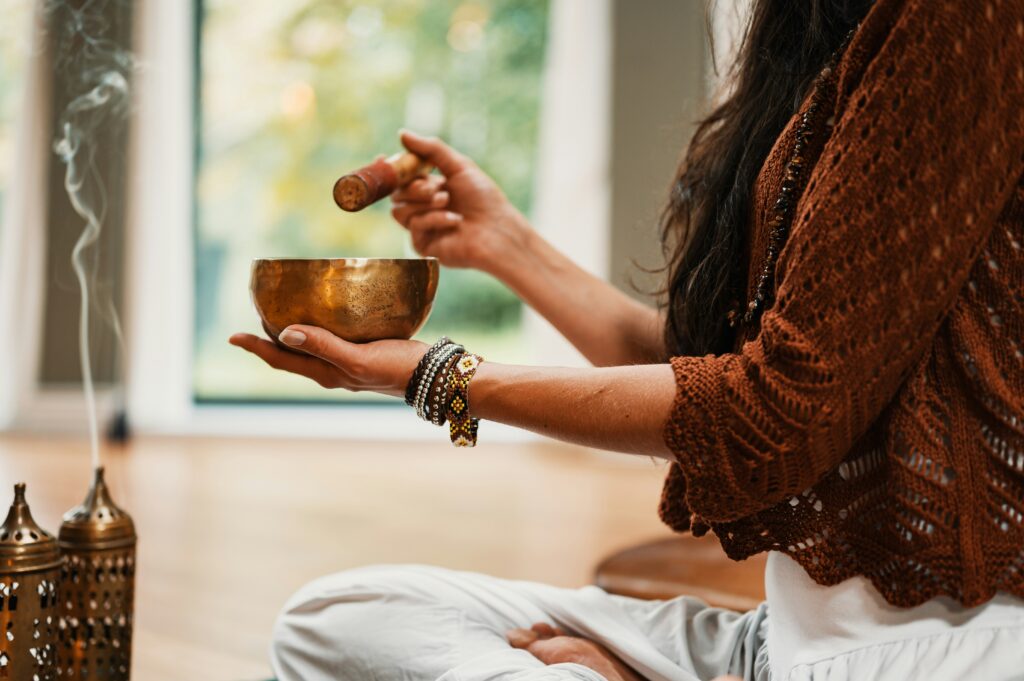 Woman using Tibetan singing bowl while burning incense.