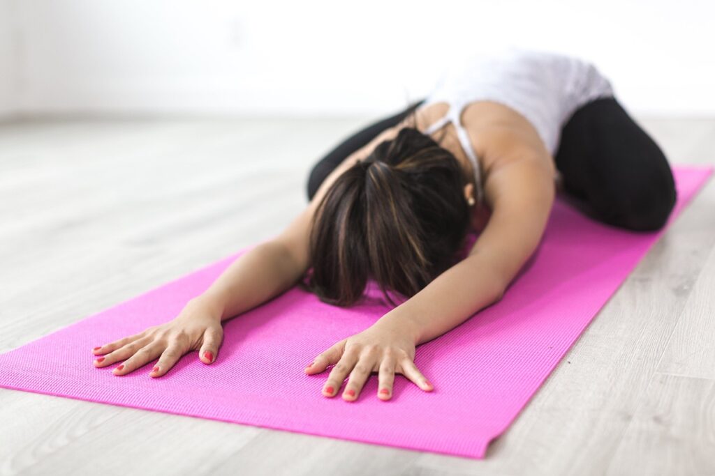 Woman doing yoga on a pink yoga mat.