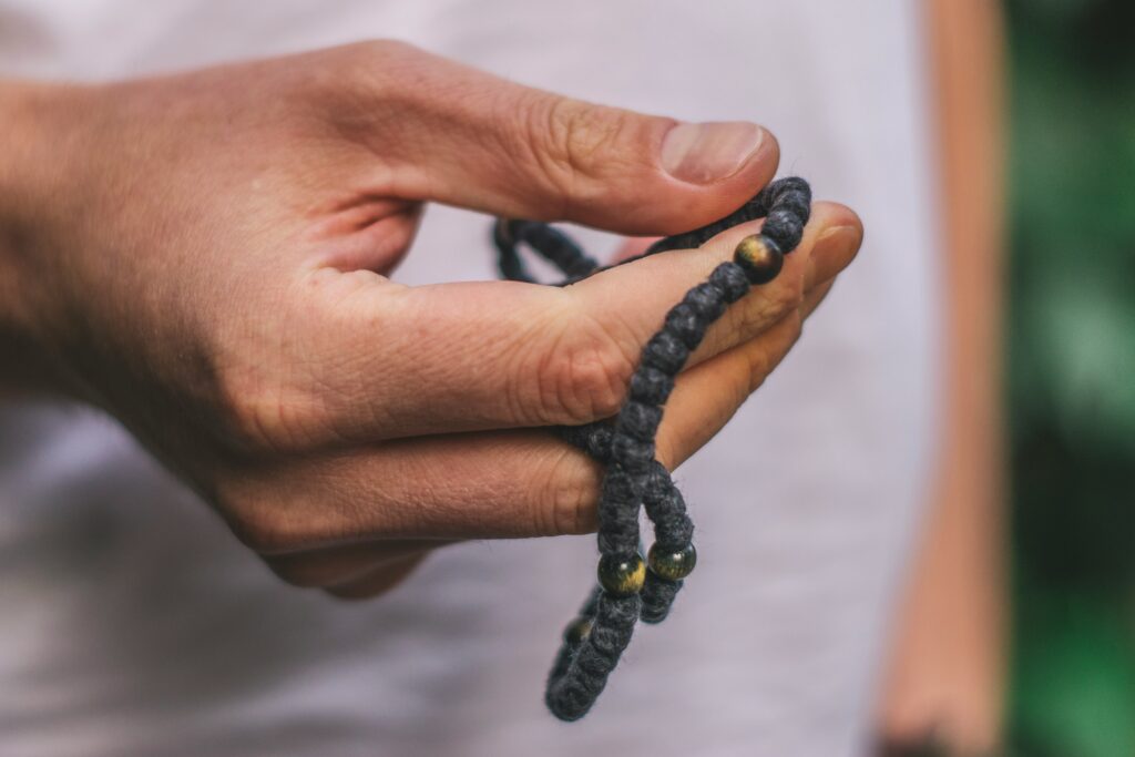 Image of a person's hand while using mala beads.