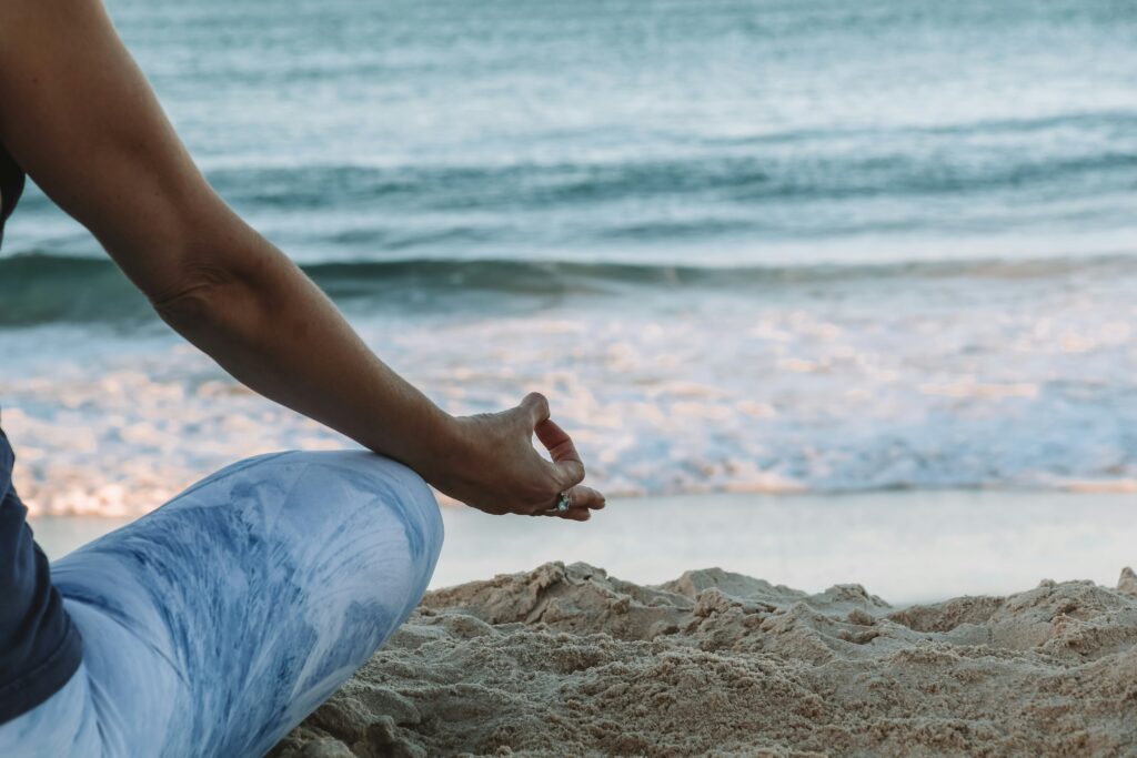 Person meditating on the beach.