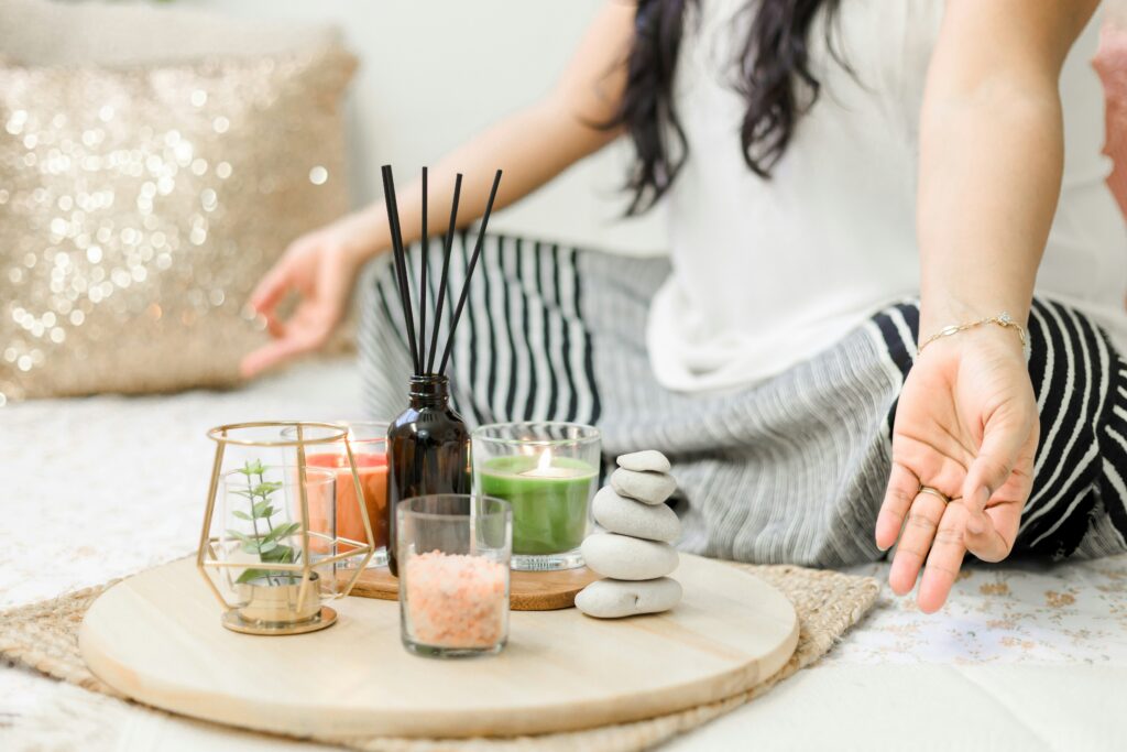 Tray of incense, candles, and meditation tools in front of a woman meditating.