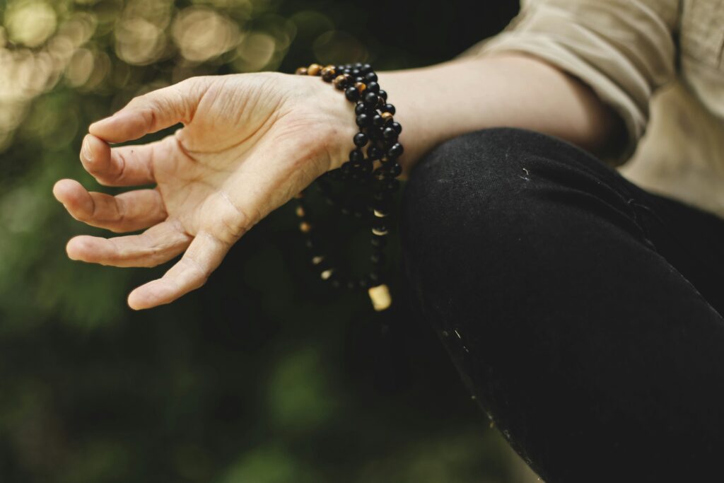 Mudra of person meditating with mala beads wrapped around their wrist.